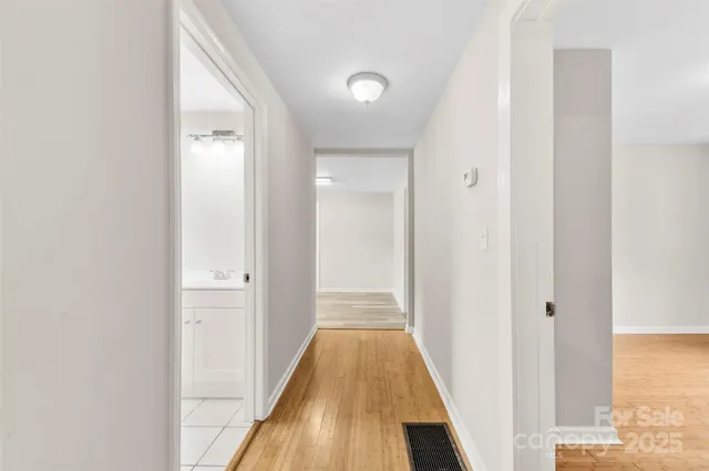 a view of a hallway with wooden floor and a bathroom