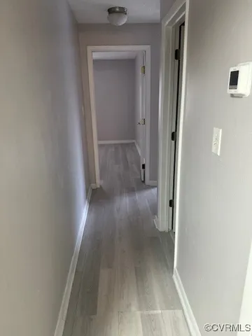a view of a hallway with wooden floor and a bathroom