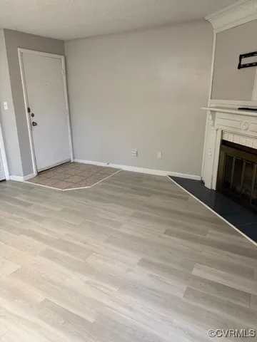 a view of empty room with wooden floor and fireplace
