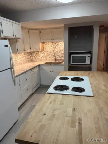 a kitchen with granite countertop a sink a stove a microwave and white cabinets
