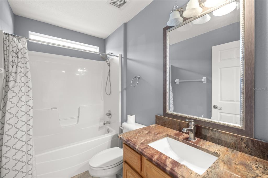 15813 Southwest 16th Avenue Road Ocala, FL 34473 - Photo 21 of 33 a bathroom with a granite countertop sink a toilet a mirror and shower