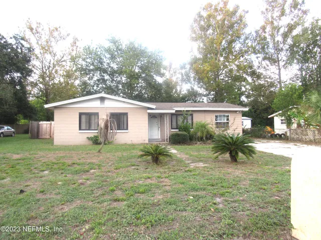 a view of a house and a yard with a large tree