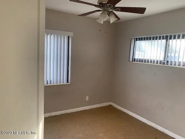 an empty room with windows and fan