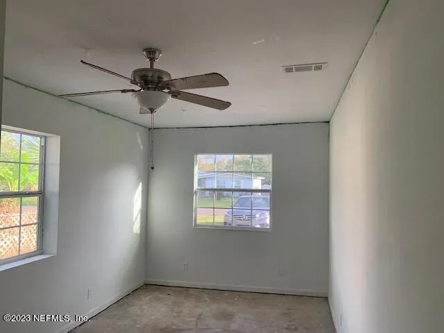 an empty room with windows and fan