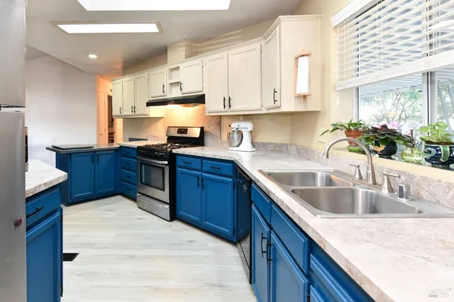 a kitchen with kitchen island granite countertop a sink dishwasher stove and cabinets with wooden floor