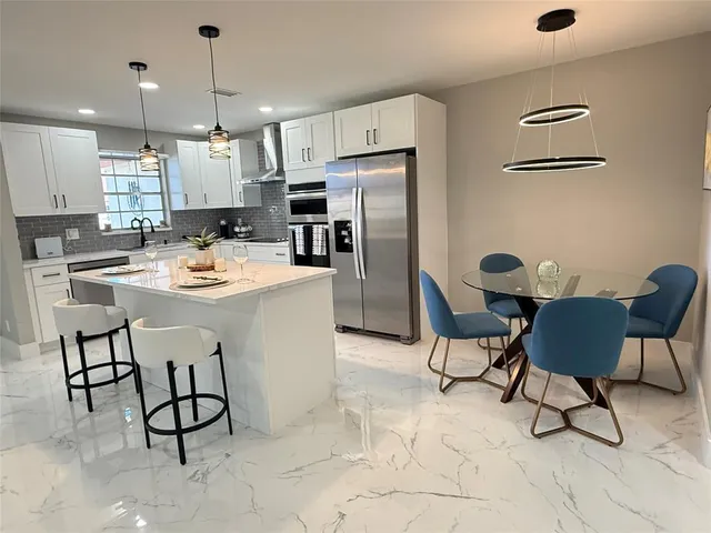 a kitchen with a dining table chairs and refrigerator