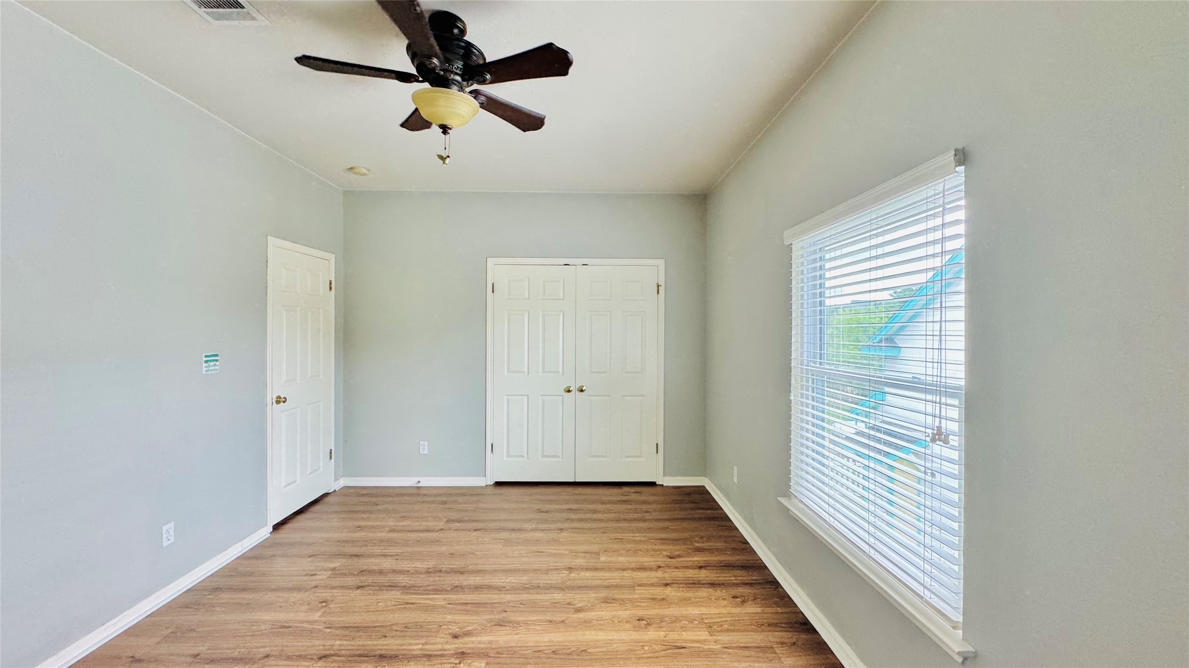 401 Witte Road Kyle, TX 78640 - Photo 18 of 24 Bedroom 3-A well-lit bedroom features sturdy wood flooring and a classic ceiling fan for comfort.