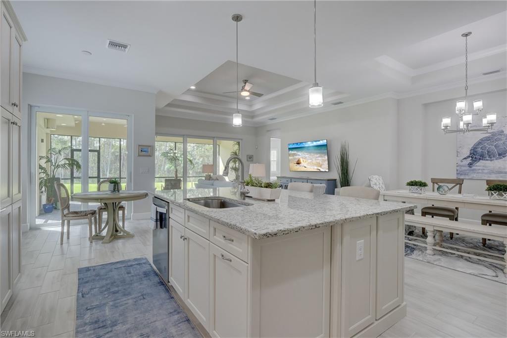 6297 Antigua Way Naples, FL 34113 - Photo 11 of 43 a kitchen with stainless steel appliances granite countertop a stove oven a dining table and chairs with wooden floor
