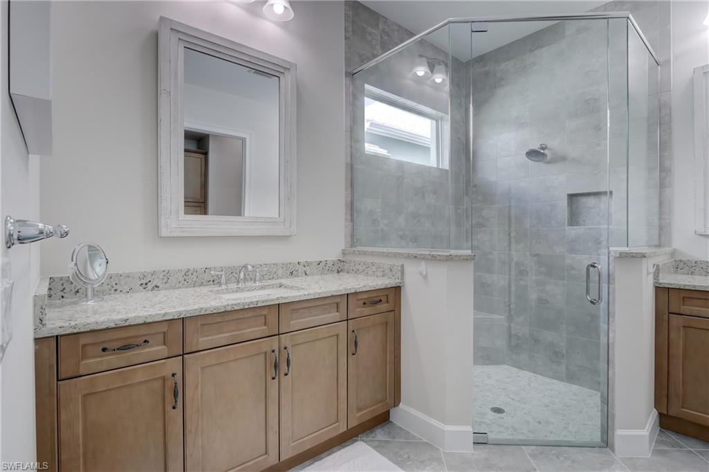 6297 Antigua Way Naples, FL 34113 - Photo 17 of 43 a bathroom with a granite countertop sink a mirror and a shower