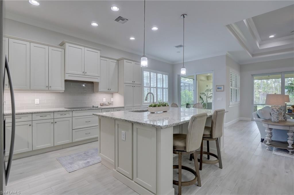 6297 Antigua Way Naples, FL 34113 - Photo 6 of 43 a kitchen with kitchen island a dining table chairs sink and cabinets
