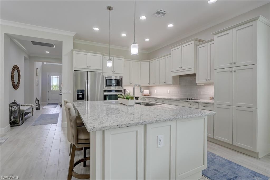 6297 Antigua Way Naples, FL 34113 - Photo 9 of 43 a kitchen with kitchen island a sink stainless steel appliances and cabinets