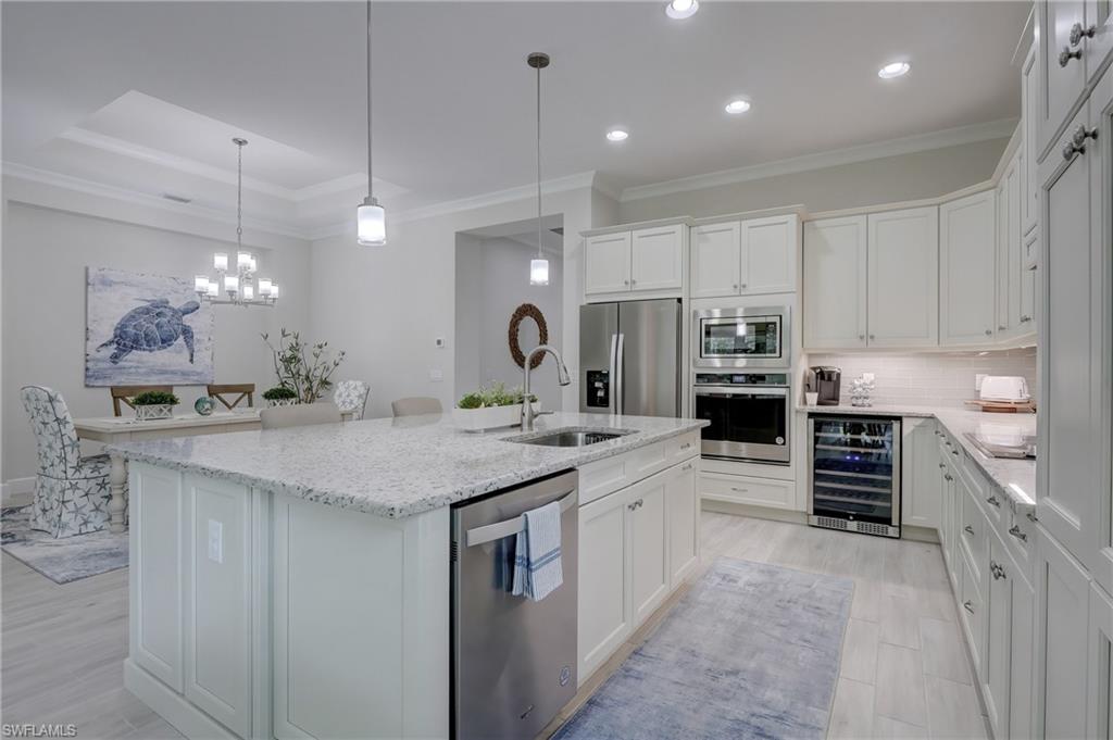6297 Antigua Way Naples, FL 34113 - Photo 10 of 43 a large kitchen with stainless steel appliances kitchen island granite countertop a sink and cabinets