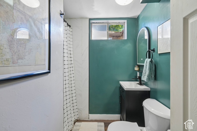 7391 Ramanee Drive Midvale, UT 84047 - Photo 29 of 45 Bathroom featuring a vanity with integrated sink, wall-mounted mirror, toilet, and a tiled shower area
