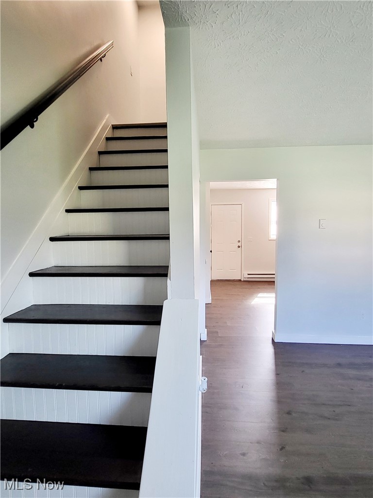 631 Root Road Lorain, OH 44052 - Photo 6 of 24 Stairway with wood-type flooring, a textured ceiling, and a baseboard heating unit