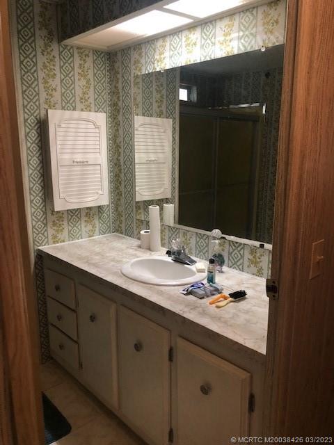 21 Los Lagos Road Port St. Lucie, FL 34952 - Photo 10 of 25 a bathroom with a granite countertop sink a large mirror and a shower