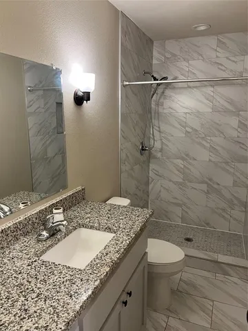 a bathroom with a granite countertop sink toilet and shower