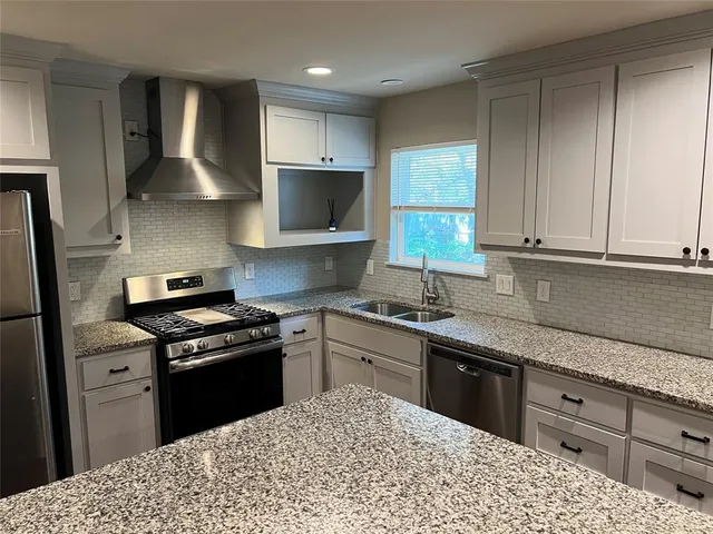 a kitchen with stainless steel appliances granite countertop a sink stove and refrigerator
