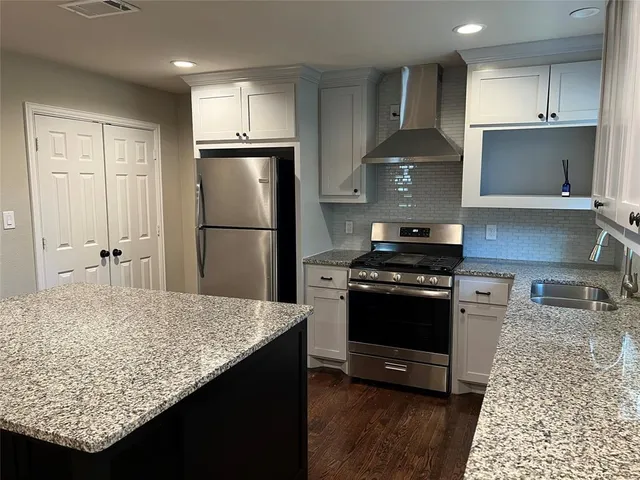 a kitchen with kitchen island granite countertop a sink stove and refrigerator