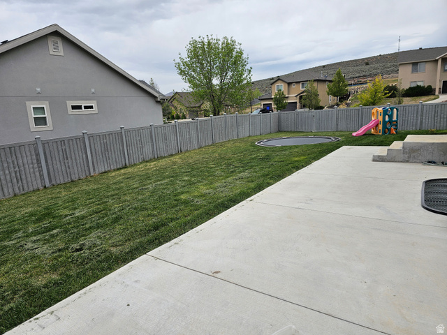 7481 Red Pine Road Eagle Mountain, UT 84005 - Photo 35 of 38 Expansive concrete patio with integrated steps provides access to a spacious lawn area and built in trampoline, enclosed by a privacy fence