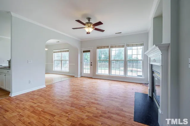 a view of an empty room with a window and wooden floor