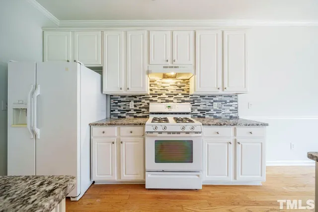 a kitchen with stainless steel appliances granite countertop a stove a white cabinet and a granite countertops