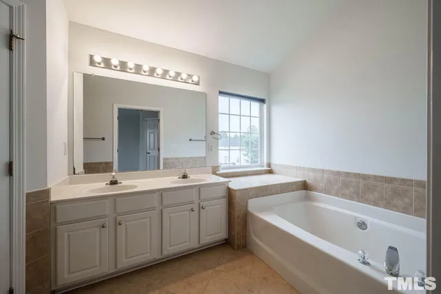 a spacious bathroom with a bathtub a sink a mirror and vanity