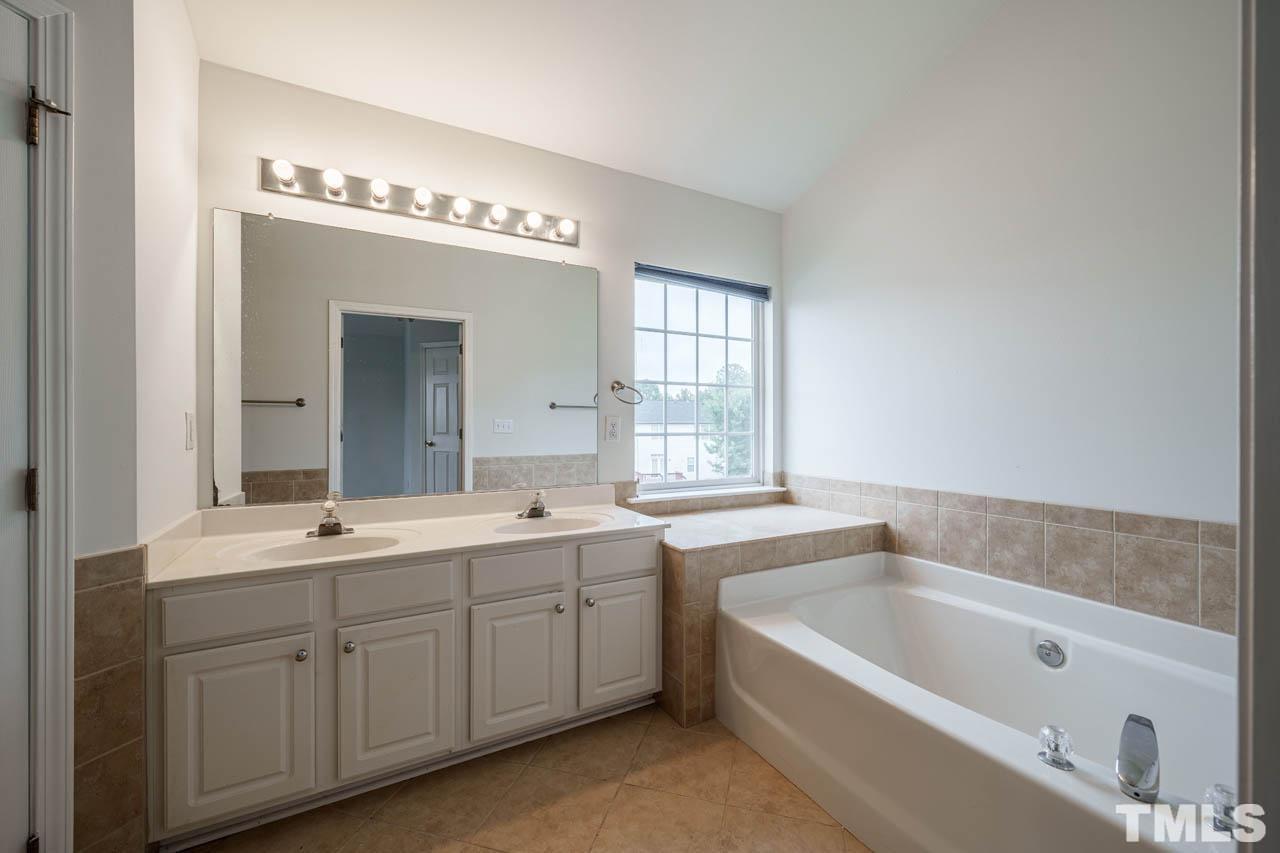 4705 Delta Vision Court, Unit (ID 12461041) Raleigh, NC 27612 - Photo 31 of 35 a spacious bathroom with a bathtub a sink a mirror and vanity