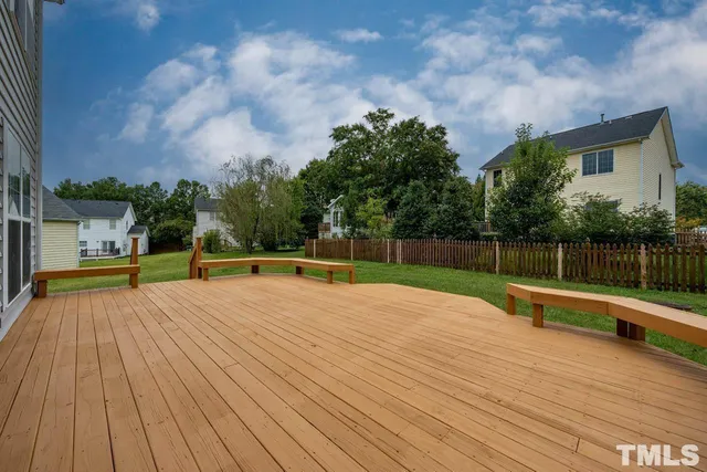 a view of swimming pool with wooden deck and trees in the background