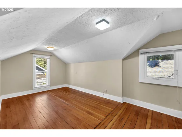 a view of an empty room with window and wooden floor