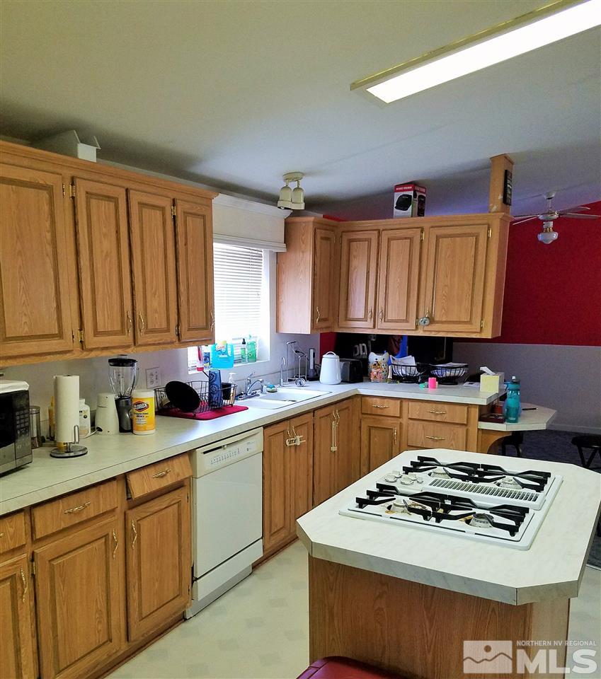 4736 Alcorn Road Fallon, NV 89406 - Photo 3 of 11 a white kitchen with a stove a sink dishwasher and cabinets with wooden floor