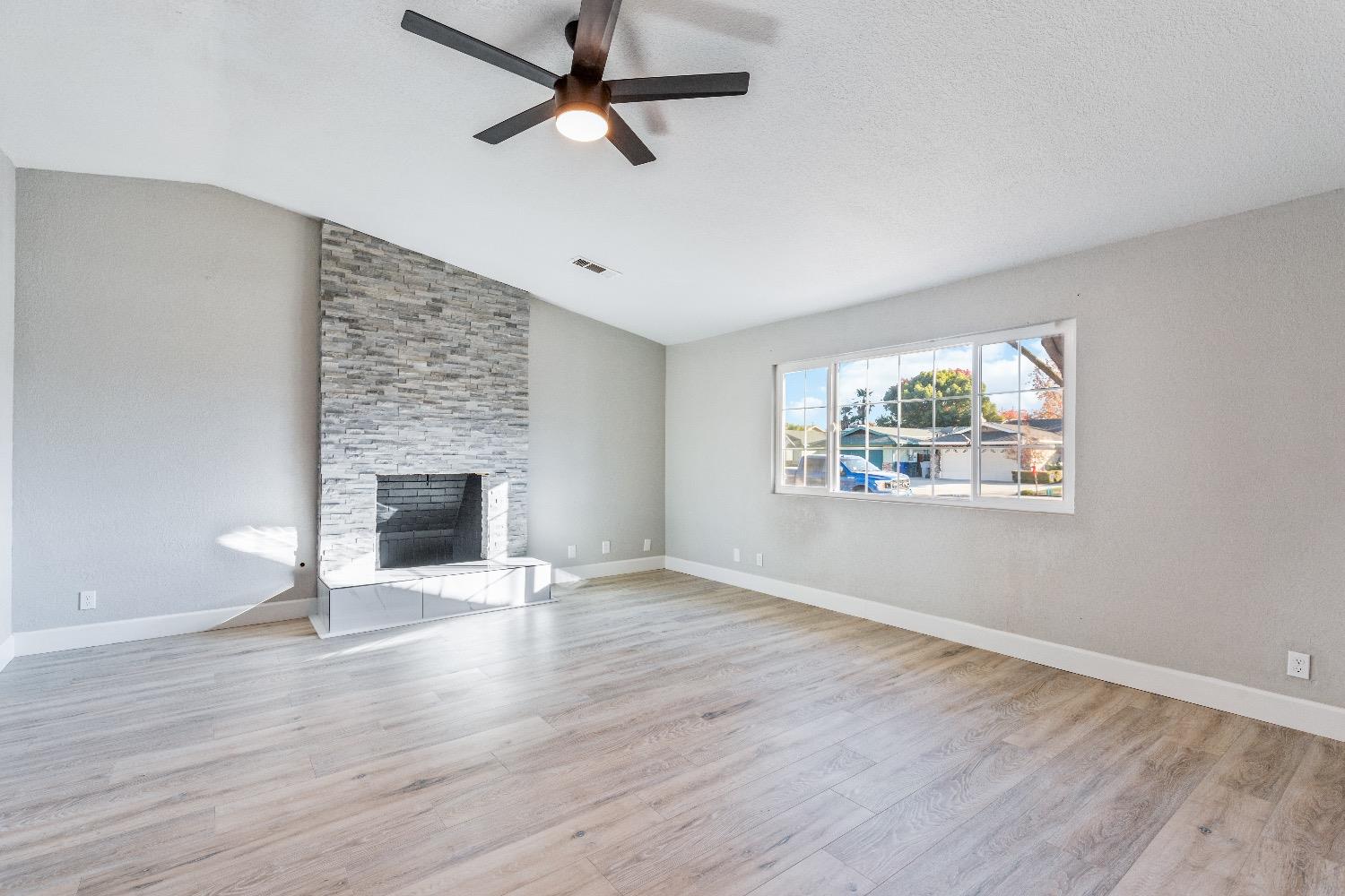 1053 Menlo Avenue Clovis, CA 93612 - Photo 7 of 41 an empty room with wooden floor fireplace and windows