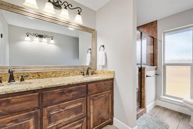 a bathroom with a granite countertop double vanity sink and a mirror