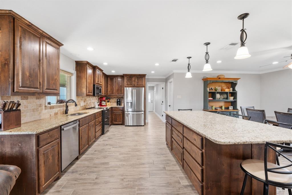 1407 Withers Road Mineral Wells, TX 76067 - Photo 8 of 38 a large kitchen with stainless steel appliances kitchen island granite countertop a large island in the center