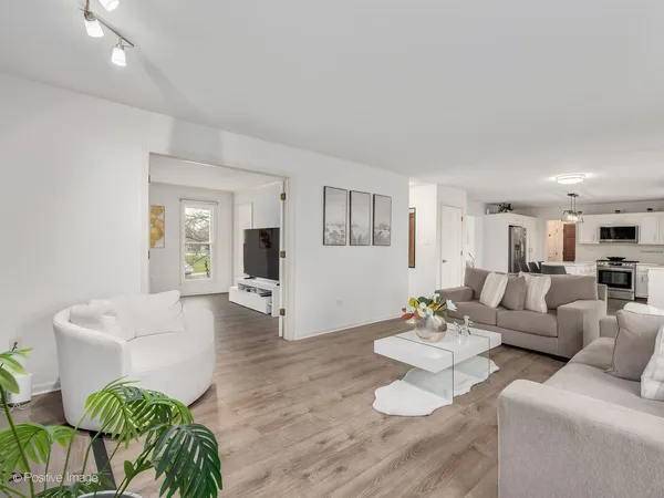 a living room with furniture and a dining table with wooden floor