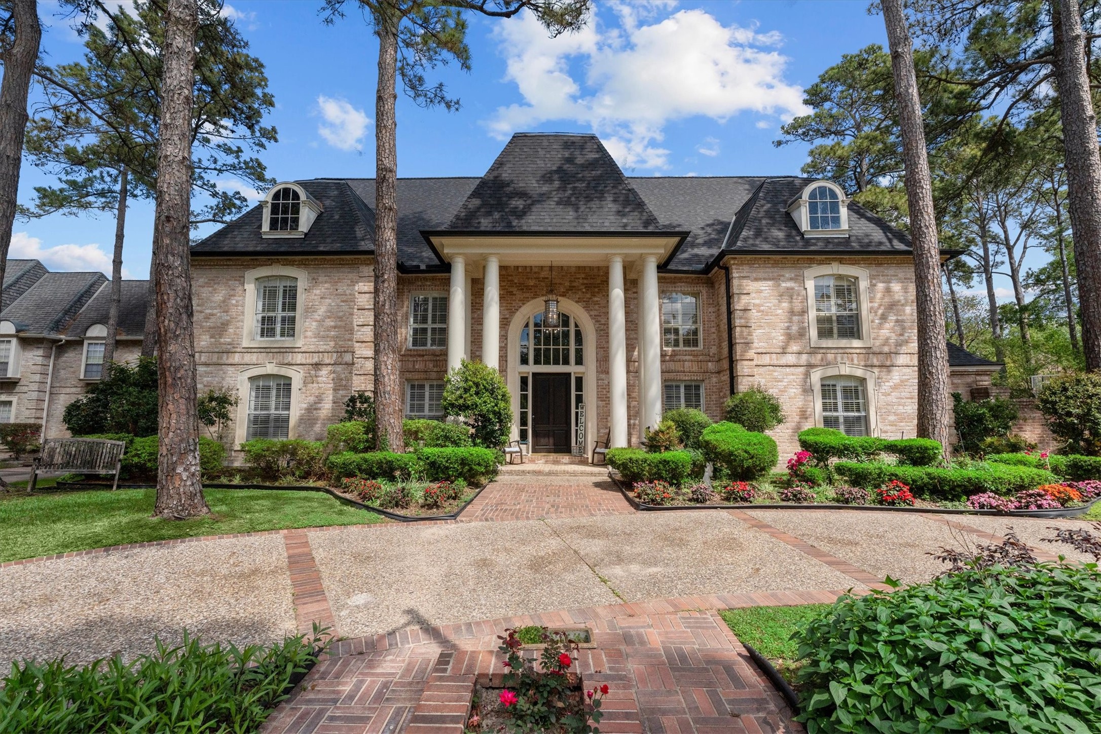 Elegant two-story home featuring a classic brick exterior with large columns framing the entrance.