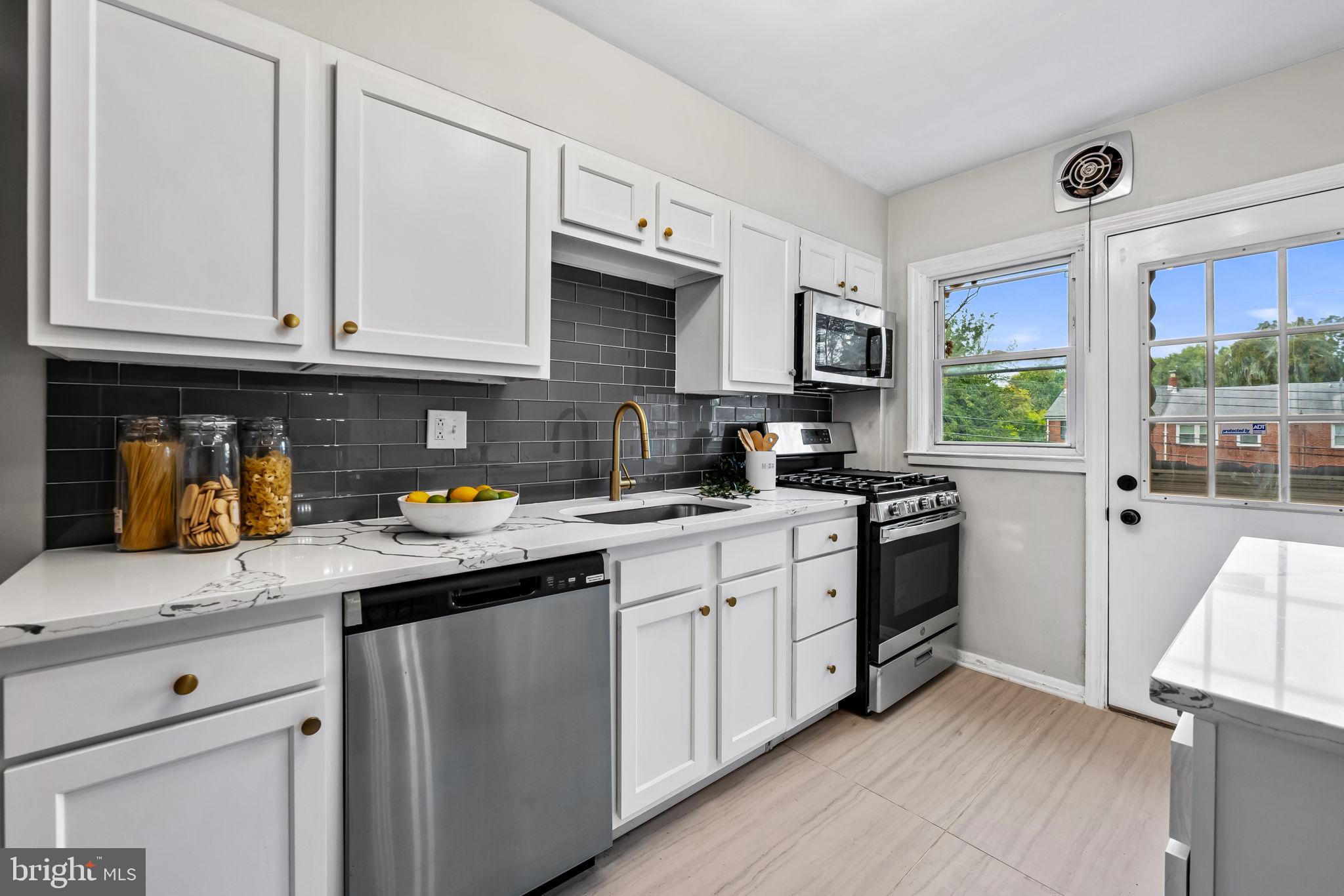 6216 Falkirk Road Baltimore, MD 21239 - Photo 9 of 27 a kitchen with stainless steel appliances granite countertop a stove a sink and white cabinets