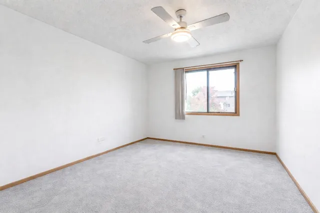 an empty room with a window and a fan