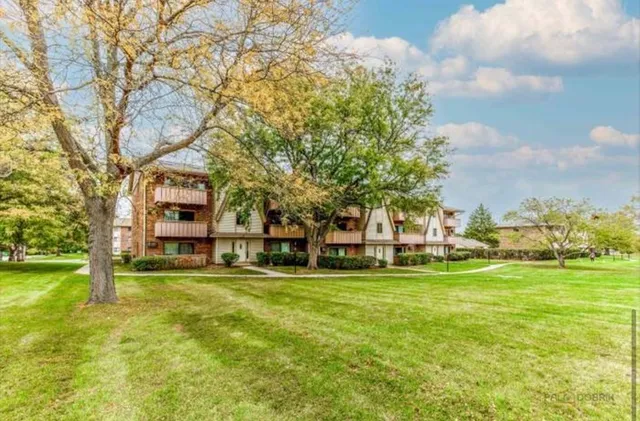 a view of a building with a big yard and large trees