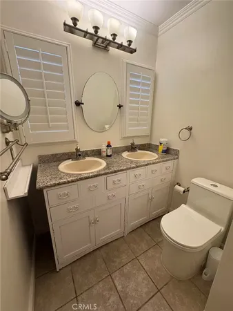 a bathroom with a granite countertop toilet sink and mirror