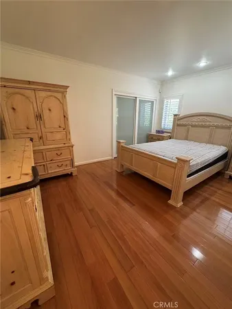 a spacious bedroom with a bed and wooden floor