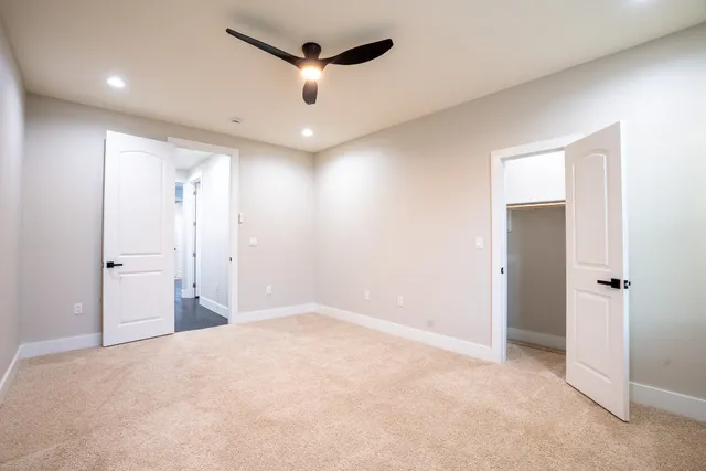 an empty room with closet and a chandelier fan