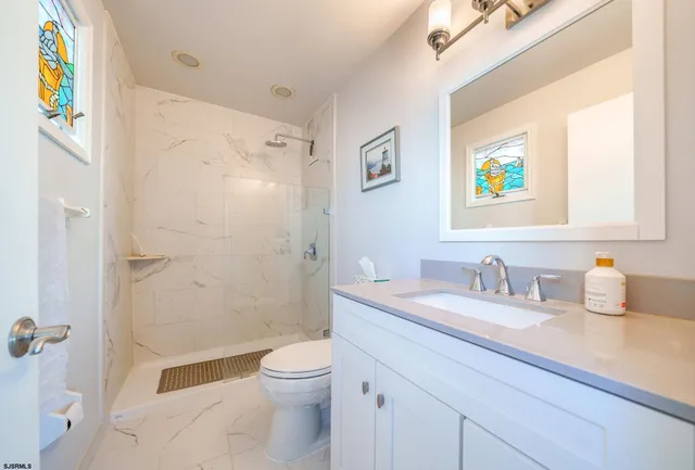a bathroom with a granite countertop sink mirror vanity and toilet