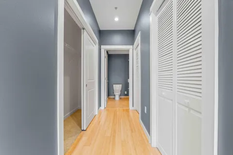 a view of a hallway with wooden floor and a bathroom