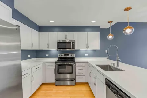 a kitchen with stainless steel appliances white cabinets sink and stove