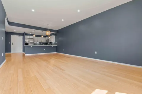a big room with wooden floor and kitchen view