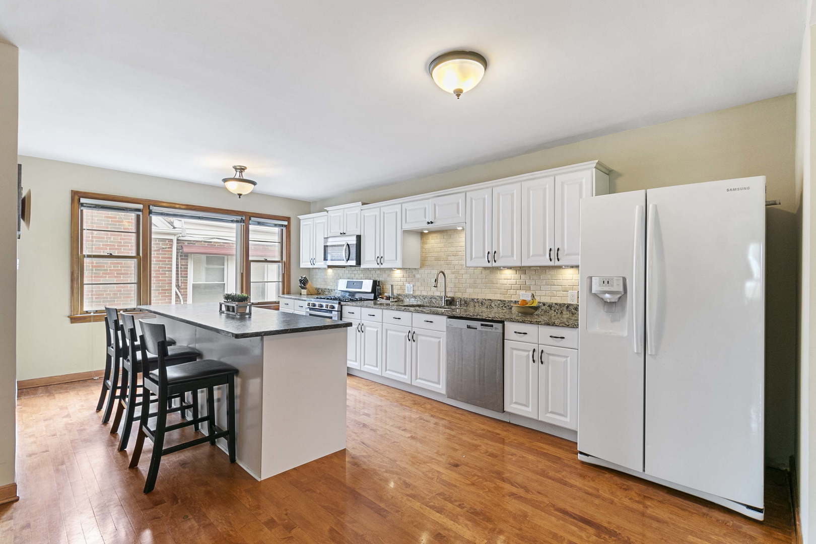 445 Uvedale Road Riverside, IL 60546 - Photo 2 of 26 a kitchen with stainless steel appliances granite countertop a refrigerator a stove a sink a dining table and chairs with wooden floor