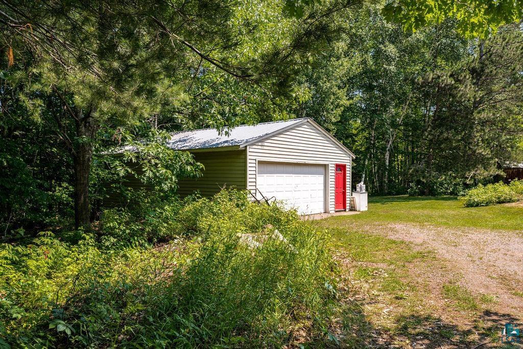 2592 Strandberg Road Barnum, MN 55707 - Photo 32 of 44 Detached garage featuring horizontal siding, a white garage door, a red side entry door, and a metal roof