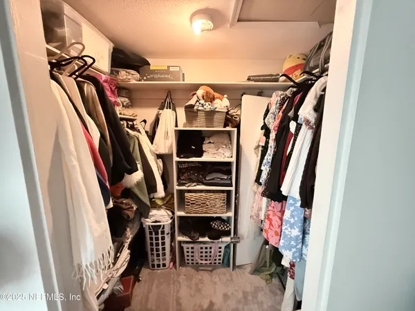 a view of walk in closet with clothes and shoes