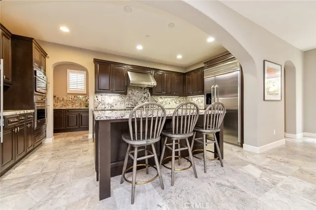 a kitchen with stainless steel appliances kitchen island granite countertop a dining table chairs and granite counter tops