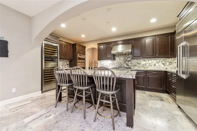 a kitchen with stainless steel appliances kitchen island granite countertop a table chairs sink and cabinets
